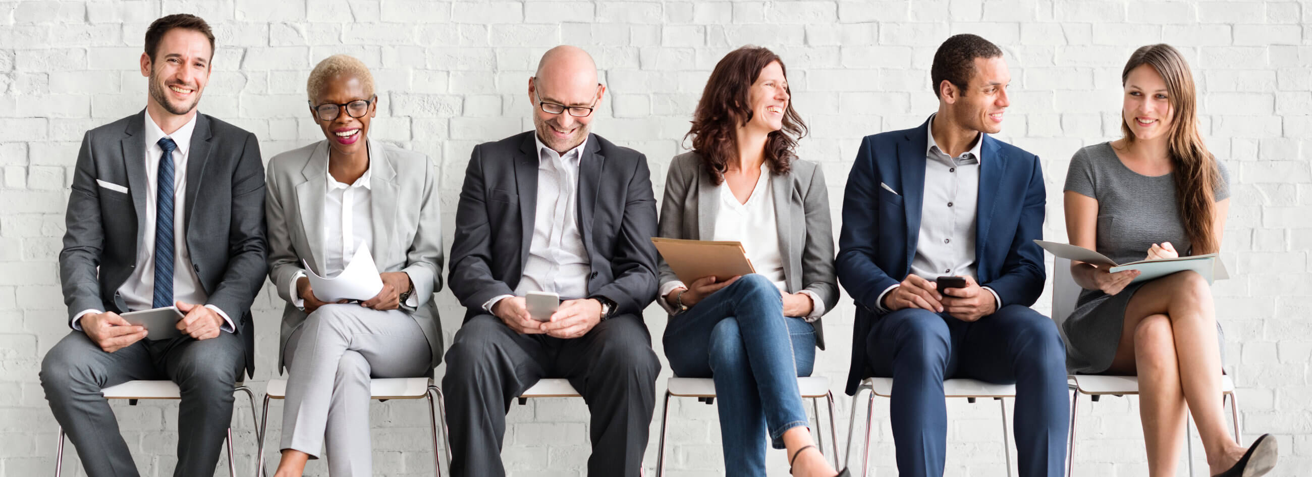 business men and women sitting on white chairs