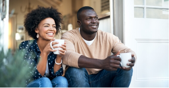 2 peple sitting on a porch drinking coffee